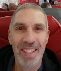 a man smiles while sitting on an airplane
